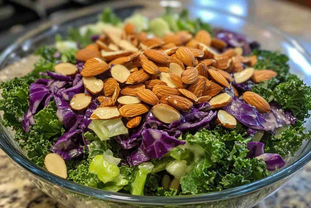 Close-up of a colorful kale salad inspired by Chick-fil-A, featuring fresh kale, shredded purple cabbage, sliced almonds, and a light dressing in a glass bowl.