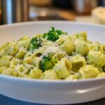 A delicious plate of broccoli pasta served in a white bowl, garnished with freshly grated parmesan cheese and parsley for a vibrant, healthy meal.