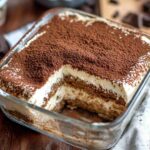 Homemade tiramisu recipe with creamy mascarpone, espresso-soaked ladyfingers, and a dusting of cocoa powder in a glass dish.